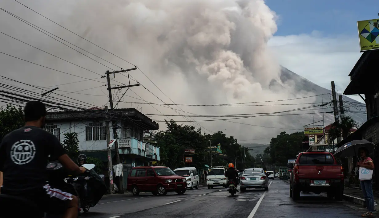 Pengendara melintasi jalanan ketika gunung Mayon mengeluarkan gumpalan asap raksasa di Camalig, selatan Manila, Senin (22/1). Filipina menaikkan Status Gunung Mayon menjadi level 4 setelah memuntahkan abu vulkanis setinggi 10 kilometer. (AFP PHOTO/STR)