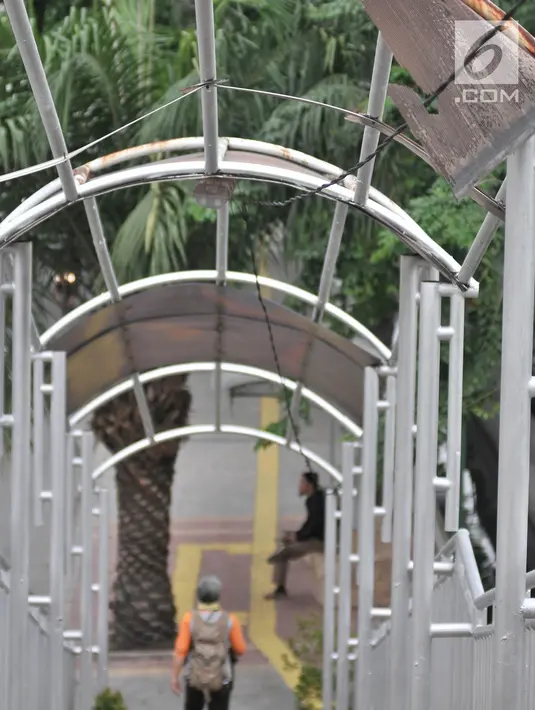 Pejalan kaki melintasi jembatan penyeberangan orang (JPO) di Jalan Yos Sudarso, Jakarta, Kamis (8/11). Kondisi JPO yang rusak menggangu kenyamanan dan keselamatan pejalan kaki. (Merdeka.com/Iqbal Nugroho)