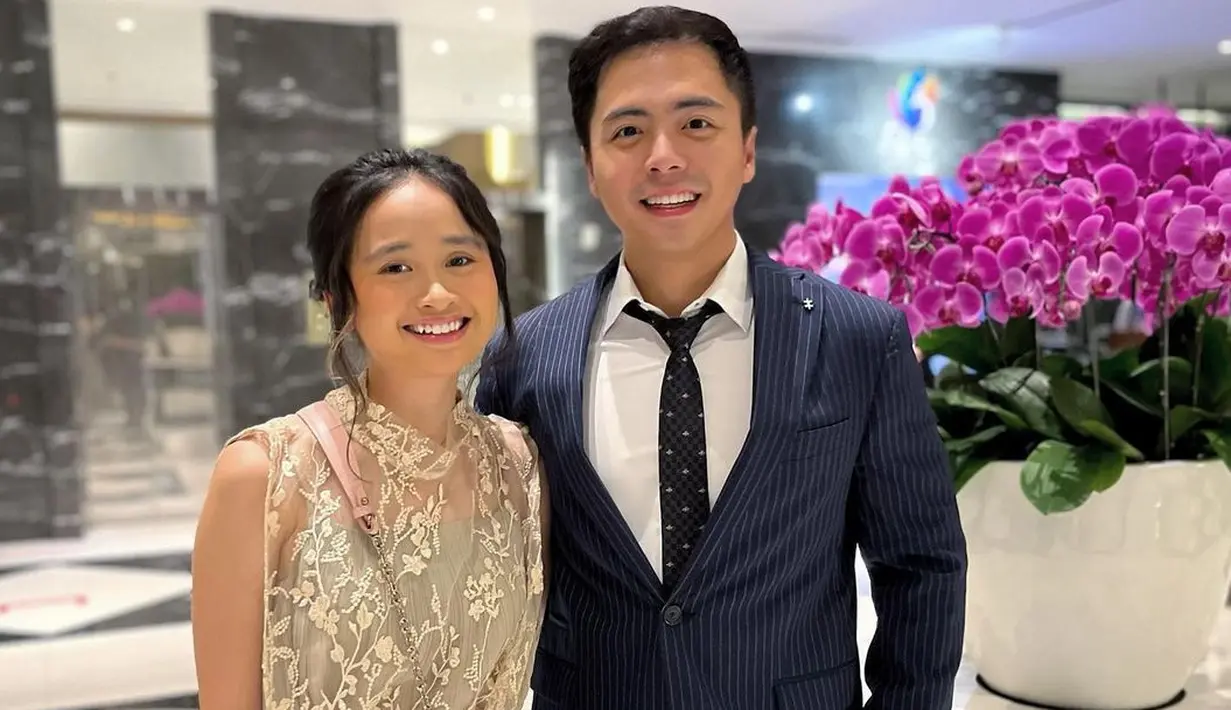 <p>Inspirasi kondangan bersama pasangan. Gritte tampil cantik dengan dress tanpa lengan bernuansa cokelat keemasan, sedangkan Arif memilih mengenakan setelan jas biru bergaris serasi dengan celananya, kemeja putih, dan dasi hitam bermotif. Foto: Instagram.</p>