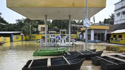 Perahu warga tampak terparkir di stasiun pengisian bahan bakar yang terendam banjir di Ghatal, distrik Paschim Medinipur, sekitar 100 km dari Kolkata (2/8/2021). Banjir parah akibat hujan lebat membuat jalanan di Ghatal berubah bak sungai. (AFP/Dibyangshu Sarkar)