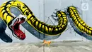 Seekor kucing melintasi depan kreasi mural di sepanjang dinding bantaran Kali Opak, Jakarta Utara, Kamis (6/2/2020). Tembok bangunan saat ini tak hanya menjadi pembatas semata tapi dimanfaatkan untuk menyampaikan pesan-pesan dan harapan dalam bentuk goresan atau tulisan. (merdeka.com/Imam Buhori)