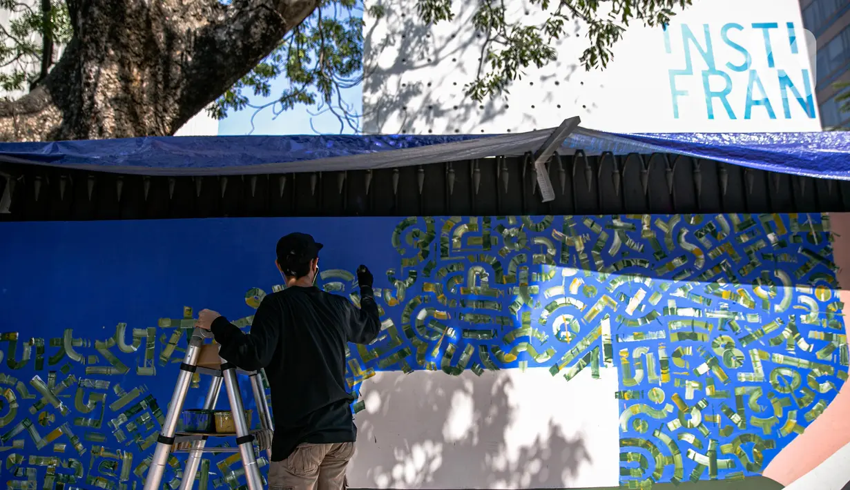 Seniman mural komunitas Converse All Stars melukis dinding Institut Perancis Indonesia (IFI) di Jalan MH. Thamrin, Jakarta, Rabu (2/12/2020). Dalam aksinya, seniman mural melukis dengan cat khusus ramah lingkungan yang diklaim bisa mengurangi polutan udara berbahaya. (Liputan6.com/Faizal Fanani)