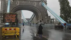 Orang-orang berjalan melewati papan tanda dekat Tower Bridge di Sungai Thames di London, Senin (9/8/2021). Tower Bridge London macet terbuka karena kesalahan teknis mengakibatkan gangguan lalu lintas di kedua sisi Sungai Thames karena mobil dan pejalan kaki tidak dapat menyeberang. (AP/Tony Hicks)