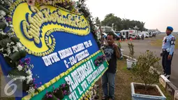 Seorang pekerja memasang karangan bunga duka di Lanud Halim Perdanakusuma, Jakarta, Rabu (1/7/2015). Karangan bunga tersebut sebagai ungkapan belasungkawa atas tragedi jatuhnya Pesawat Hercules C-130 di Medan. (Liputan6.com/Faizal Fanani)