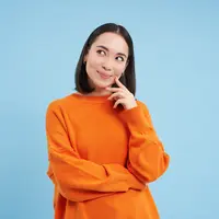 Seorang perempuan berbaju oranye sedang berpikir sambil memegang pipinya menggunakan telunjuk (Foto Dok: Freepik/benzoix).