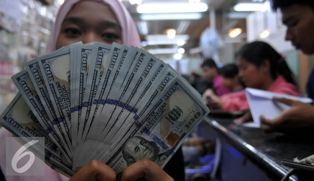 Petugas menunjukan uang pecahan US$100 di penukaran uang Jakarta, Senin (24/8/2015). Nilai tukar rupiah terhadap dolar Amerika Serikat (AS) terus menguat, Posisi dolar terus beranjak hingga di kisaran Rp 14.150. (Liputan6.com/Johan Tallo)