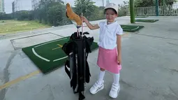Seakan tak mau kalah dari sang mama, Claire juga tampil sporty dengan baju putih dan rok pink. Kaus kaki dan sepatunya juga berwarna putih, ditambah topi caddy yang senada. Claire tampak manis dengan senyumannya yang percaya diri. (Liputan6.com/IG/@shandyaulia)