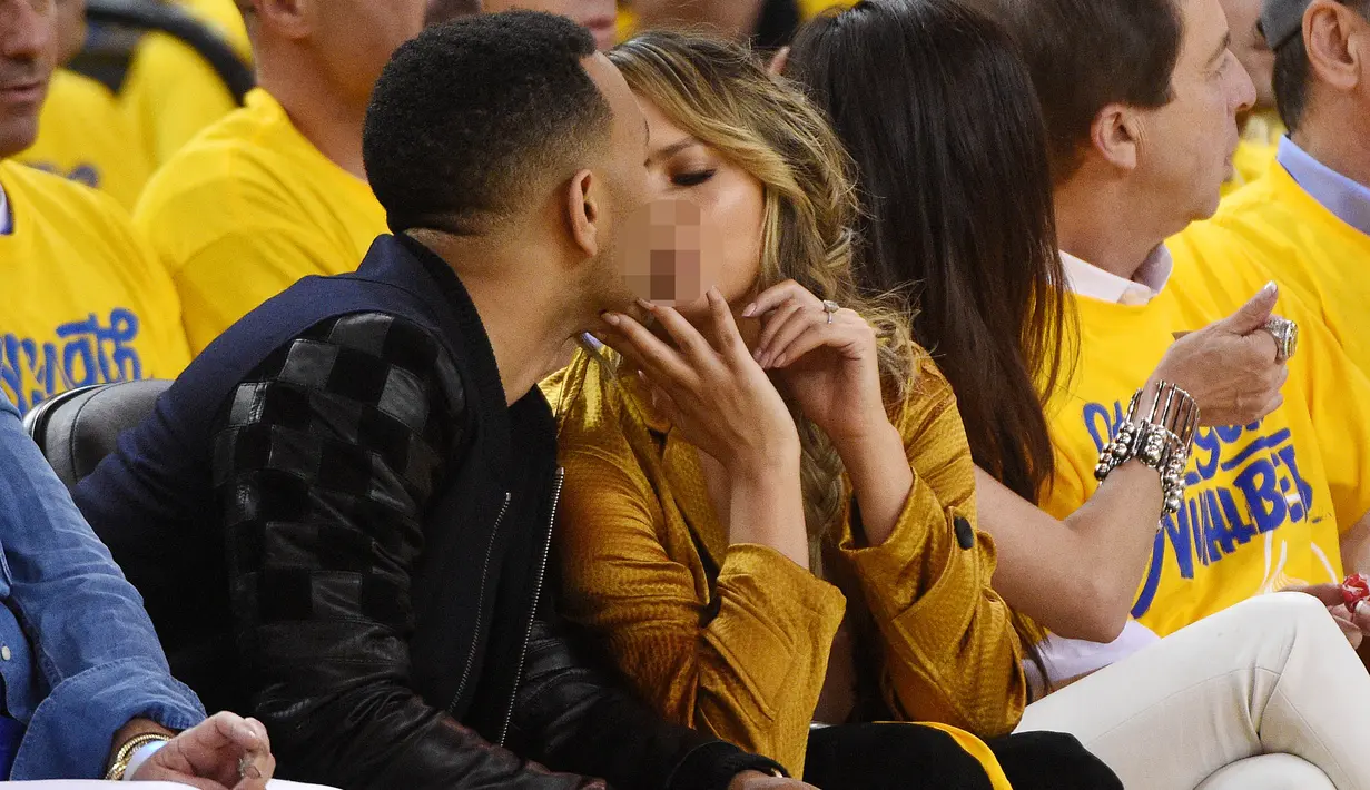 Penyanyi, John Legend bersama sang istri Chrissy Teigan terlihat berciuman saat menonton pertandingan final NBA 2016 antara Golden State Warriors dan Cleveland Cavaliers di Oracle Arena, California, USA (2/6/2016). (Kyle Terada-USA TODAY Sports)