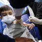 Seorang anak laki-laki menerima dosis vaksin covid-19 Pfizer-BioNTech di pusat vaksinasi di Kuwait International Fairground di Kuwait City pada 3 Februari 2022. Kementerian kesehatan Kuwait mulai memvaksinasi anak usia 5 hingga 11 tahun. (YASSER AL-ZAYYAT / AFP)