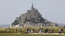 <p>Orang-orang berjalan melewati Biara Mont-Saint-Michel saat kunjungan Presiden Prancis Emmanuel Macron di Normandia, Le Mont-Saint-Michel, Prancis, Senin (5/6/2023). (Ludovic MARIN/POOL/ AFP)</p>