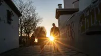 Pasangan berjalan melalui distrik bersejarah Albaicin saat matahari terbenam di Granada, Spanyol, (12/3). Distrik ini dinyatakan sebagai Situs Warisan Dunia UNESCO pada tahun 1984. (AP Photo/Mosa'ab Elshamy)