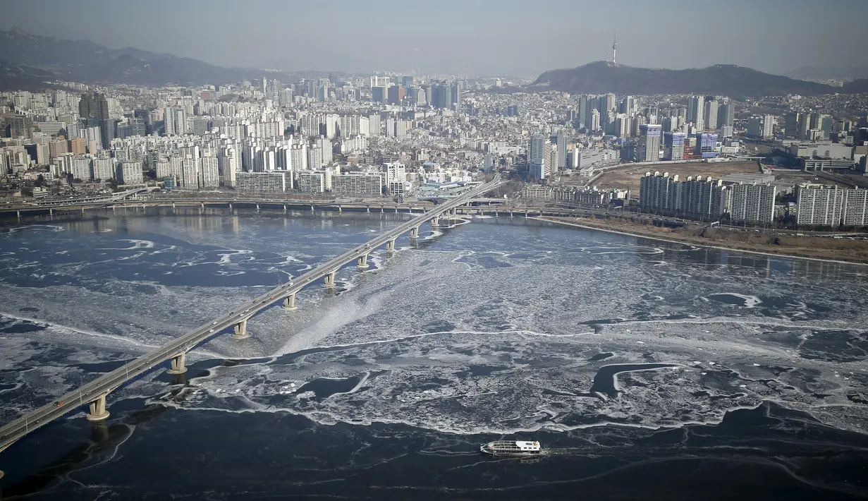 Sebuah kapal penumpang (bawah) menyeberangi aliran es di Sungai Han yang membeku di Seoul, Korea Selatan, Senin (25/1). Sungai Han membeku akibat suhu di Korea yang kini mencapai minus dol derajat Celsius. (REUTERS/Kim Hong - Ji)