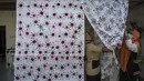 Penyandang disabilitas menjemur kain batik dengan motif virus corona di Surabaya, Jawa Timur (19/8/2020). Di tengah pandemi Covid-19, sekelompok penyandang disabilitas di Surabaya membuat batik bermotifkan virus corona. (AFP/JUNI KRISWANTO)