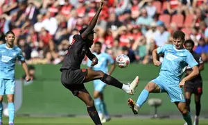 Bek Bayer Leverkusen asal Burkina Faso #12, Edmond Tapsoba, dan penyerang Hoffenheim asal Jerman #11, Fisnik Asllani, berebut bola dalam pertandingan divisi satu Bundesliga Jerman antara Bayer 04 Leverkusen dan TSG 1899 Hoffenheim di Leverkusen, Jerman Barat, pada 23 Agustus 2025. (INA FASSBENDER/AFP)