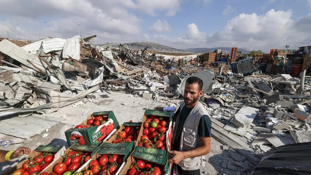 Seorang pedagang Palestina memajang barang dagangan mereka di dekat reruntuhan setelah tentara Israel menghancurkan enam belas toko di pasar hasil bumi di desa Beita, selatan Nablus, di Tepi Barat yang diduduki. (Dok. AFP)