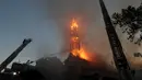 Petugas pemadam kebakaran memadamkan gereja La Asuncion setelah diserang dan dibakar saat puluhan ribu orang berunjuk rasa di Kota Santiago, Chile, Minggu (18/10/2020). Demonstrasi itu digelar untuk memperingati satu tahun protes besar menuntut kesetaraan di Chile. (AP Photo/Esteban Felix)