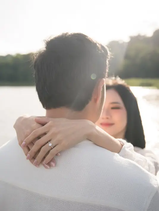 Cahaya matahari sore menambah kesan hangat, menciptakan suasana intim yang tak terlupakan. Sang kekasih, dengan penuh kasih, memasangkan cincin ke jari manis Jessica sambil tersenyum bahagia. [@jessicajane99].