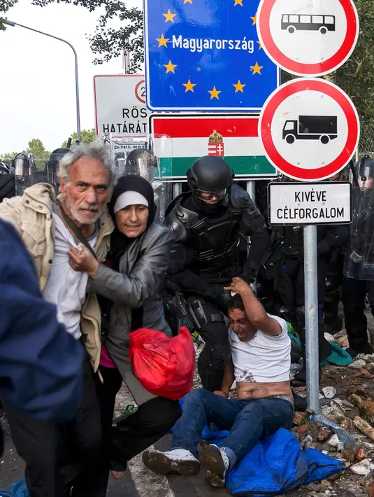 Dua imigran menyelamatkan diri dari polisi dengan imigran yang berusaha menerobos pintu perbatasan antara Serbia dan Hungaria di Roszke, Rabu (16/9/2015). (REUTERS/Marko Djurica)