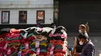 Orang-orang membeli pakaian dari kios-kios yang didirikan di luar gedung bioskop di New Delhi (29/12/2021). Pemerintah Delhi memberlakukan pembatasan fasilitas seperti gedung bioskop, multipleks, dan gym, dan lainya untuk mengekang lonjakan virus corona Covid-19. (AFP Photo/Sajjad Hussain)