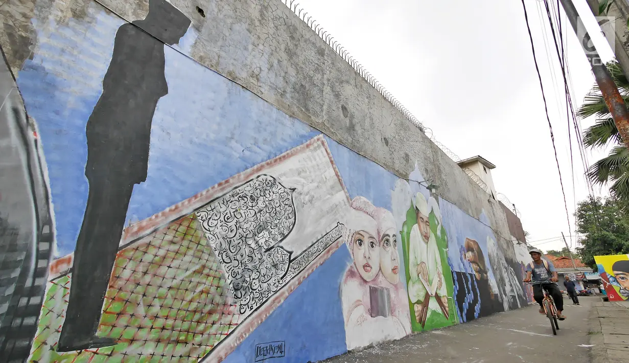 Pengendara sepeda melintas di depan dinding berhias mural bertema Islami di Gang Abdul Jabar, Jagakarsa, Jakarta, Senin (28/5). (Liputan6.com/Herman Zakharia)