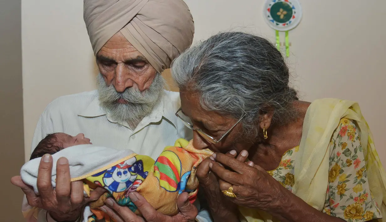 Pasangan Daljinder Kaur (kiri) bersama sang suami Mohinder Singh Gill saat menggendong bayi kesayangan mereka di Amritsar, India, Rabu (11/5).Nenek berusia 70 tahun ini berhasil melahirkan seorang bayi laki-laki bernama Armaan.( NARINDER NANU / AFP)