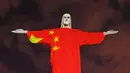 Patung Christ the Redeemer atau patung Yesus sang Penebus yang populer di dunia menyala dengan gambar bendera China pada hari Paskah di Rio de Janeiro, Brasil, Minggu (12/4/2020). Pertunjukkan itu bentuk dukungan dan semangat untuk melawan pandemi COVID-19. (CARL DE SOUZA/AFP)