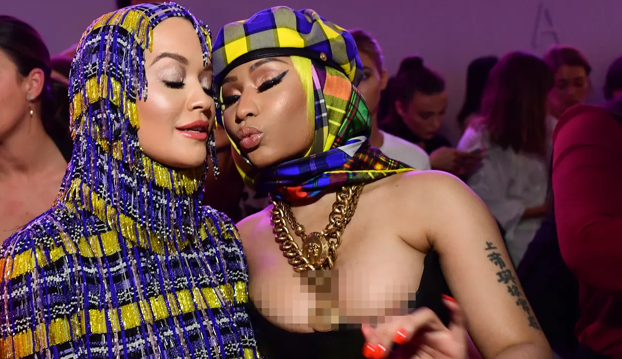 Penyanyi Rita Ora (kiri) dan rapper AS, Nicki Minaj menghadiri fashion show Versace pada Milan Fashion Week, 21 September 2018. Seperti biasa Nicki Minaj yang dikenal dengan keseksiannya tampil mencuri perhatian di fashion show itu. (AFP/Miguel MEDINA)