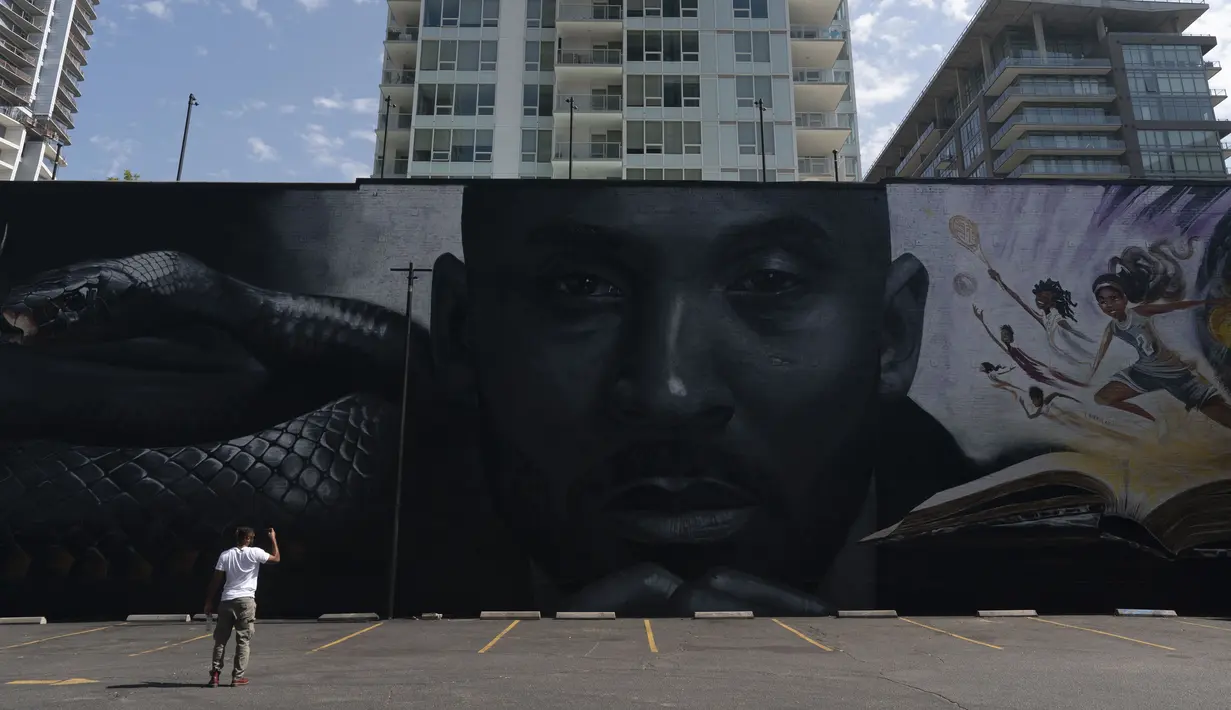 Nate Edwards mengambil gambar mural yang menggambarkan Kobe Bryant dan putrinya, Gianna, di Los Angeles, Rabu, 24 Agustus 2022. Mural, yang dilukis oleh seniman jalanan Portugis Odeith dan seniman dan ilustrator kontemporer Amerika Nikkolas Smith tersebut untuk merayakan Kobe Bryant Day. (AP Photo/Jae C. Hong)