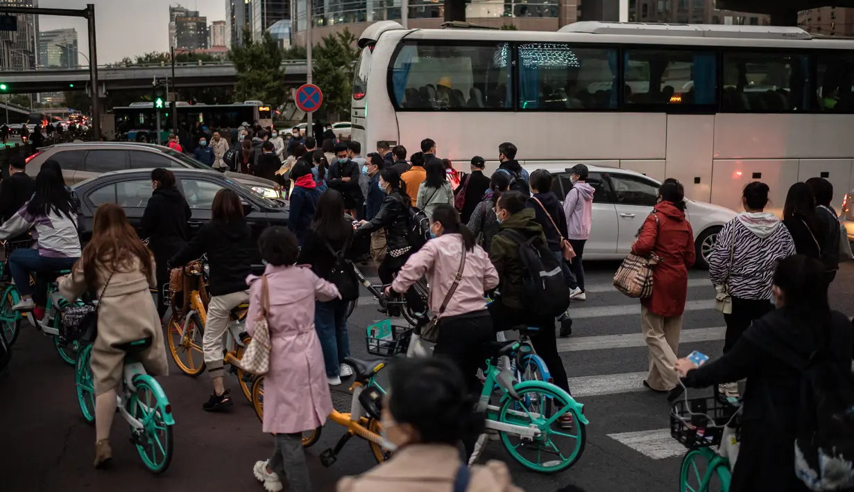 Orang-orang mencoba melewati lalu lintas saat mereka bepergian dengan sepeda selama jam sibuk di Beijing, China pada 14 Oktober 2020. (Photo by NICOLAS ASFOURI / AFP)