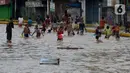 Anak-anak bermain air saat banjir menggenangi Jalan Jatinegara Barat, Jakarta, Kamis (2/1/2020). Hujan yang terjadi kemarin malam membuat Kali Ciliwung meluap ke jalan. (merdeka.com/Imam Buhori)