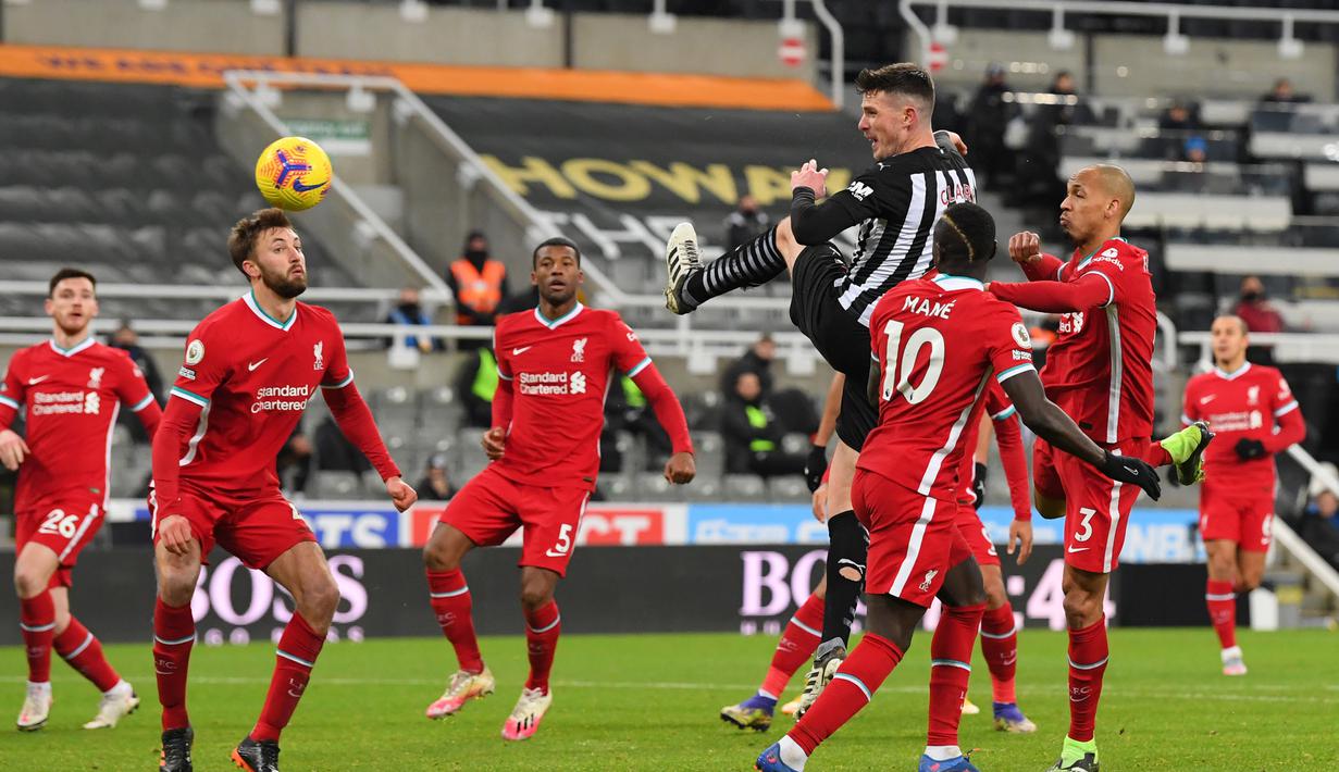 Bek Newcastle United, Ciaran Clark melepaskan sundulan sambil melompat ke gawang Liverpool dalam laga lanjutan Liga Inggris 2020/21 pekan ke-16 di St James' Park, Rabu (30/12/2020). Newcastle United bermain imbang 0-0 dengan Liverpool. (AFP/Stu Forster/Pool)