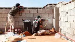 Para pasukan militer pemerintah Libya melepaskan tembakan dari lubang beton saat melakukan serangan ke pada para pejuang ISIS dari atap atap rumah di daerah Zaafran, di Sirte, Libya, 30 Juni 2016. (REUTERS/Ismail Zitouni)