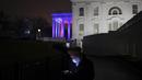 Seorang pria memeriksa ponselnya saat Gedung Putih diterangi dengan warna merah, putih dan biru untuk mendukung Tim Olimpiade dan Paralimpiade AS pada 03 Februari 2022 di Washington, DC. Olimpiade Musim Dingin Beijing 2022 berlangsung mulai 4 hingga 20 Februari. (Win McNamee/Getty Images/AFP)