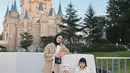 Di depan istana Disneyland, Dwi Handayani berpose bersama 2 buah hatinya. Dwi Handayani mengenakan long coat cokelat yang dipadu dengan celana panjang hitam. Sedangkan kedua anaknya terlihat mengenakan outfit senada berwarna putih. Foto: Instagram.