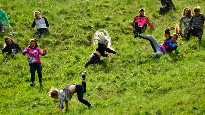 Peserta berlomba mengejar keju dalam kompetisi Cheese Rolling di Bukit Cooper, Gloucestershire, Inggris, Senin (27/5/2019). Ada lima sesi kompetisi balapan menggelindingkan keju dalam festival ini, yaitu 4 sesi untuk pria dan satu sesi untuk wanita. (Ben Birchall/PA via AP)