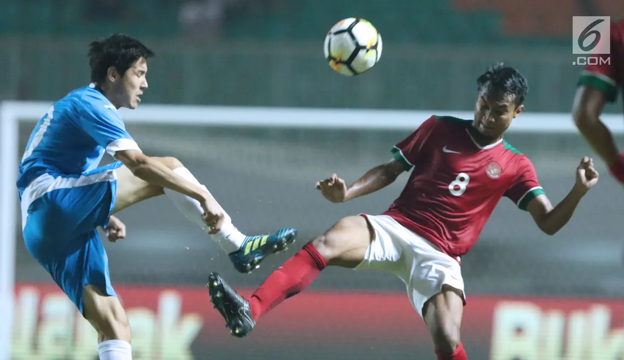 Gelandang Indonesia U-23, M Hargianto (kanan) berebut bola atas dengan pemain Uzbekistan, Alikulov Khusniddin pada laga PSSI Anniversary 2018 di Stadion Pakansari, Kab Bogor, Kamis (3/5). Laga imbang 0-0. (Liputan6.com/Helmi Fithriansyah)