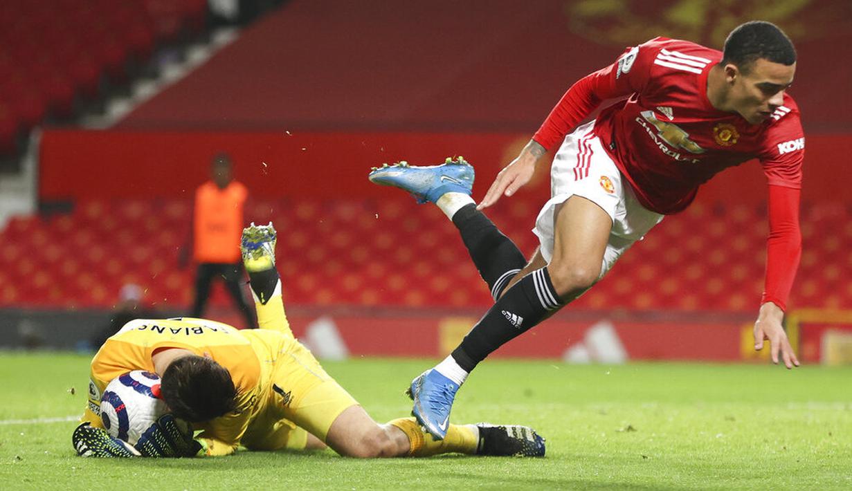 Penyerang Manchester United, Mason Greenwood, terjatuh saat berebut bola dengan kiper West Ham United, Lukasz Fabianski, pada laga Liga Inggris di Stadion Old Trafford, Minggu (15/3/2021). Setan Merah menang dengan skor 1-0. (AP/Clive Brunskill,Pool)