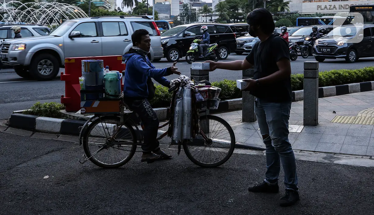 Pewarta Foto membagikan takjil kepada pejalan kaki di Kawasan Bundaran HI, Jakarta, Selasa (20/4/2021). Kegiatan berbagi takjil yang digagas oleh Pewarta Foto Indonesia Jakarta (PFIJ) ini dilaksanakan setiap hSelasa dan Jumat selama bulan Ramadhan sebagai bentuk solidaritas (Liputan6.com/JohanTallo)
