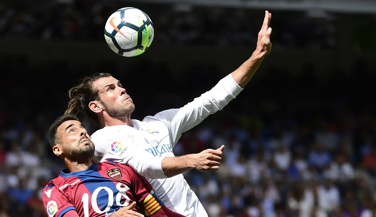 Pemain Levante, Pedro Lopez (kiri) berebut bola dengan pemain Real Madrid, Gareth Bale pada lanjutan La Liga di Santiago Bernabeu stadium, Madrid (9/9/2017). Madrid bermain imbang 1-1. (AFP/Pierre-Philippe Marcou)
