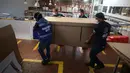 Pekerja perusahaan membawa produk berisi rekan mereka saat mendemonstrasikan desain kardus yang dapat berfungsi sebagai tempat tidur rumah sakit dan peti mati di Bogota, Kolombia, Jumat (8/5/2020). Perusahaan ini menanggapi kekurangan tempat tidur dan peti mati selama pandemi.  (AP/Fernando Vergara)