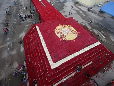 Penduduk setempat menyelesaikan pembuatan piramida Cochasqui dari bunga mawar dalam upaya pemecahan Guinness World Records di Tabacundo, Ekuador, 20 Juli 2018. Piramida dibangun di lahan seluas 1.100 meter tanpa henti oleh para relawan (AP/Dolores Ochoa)