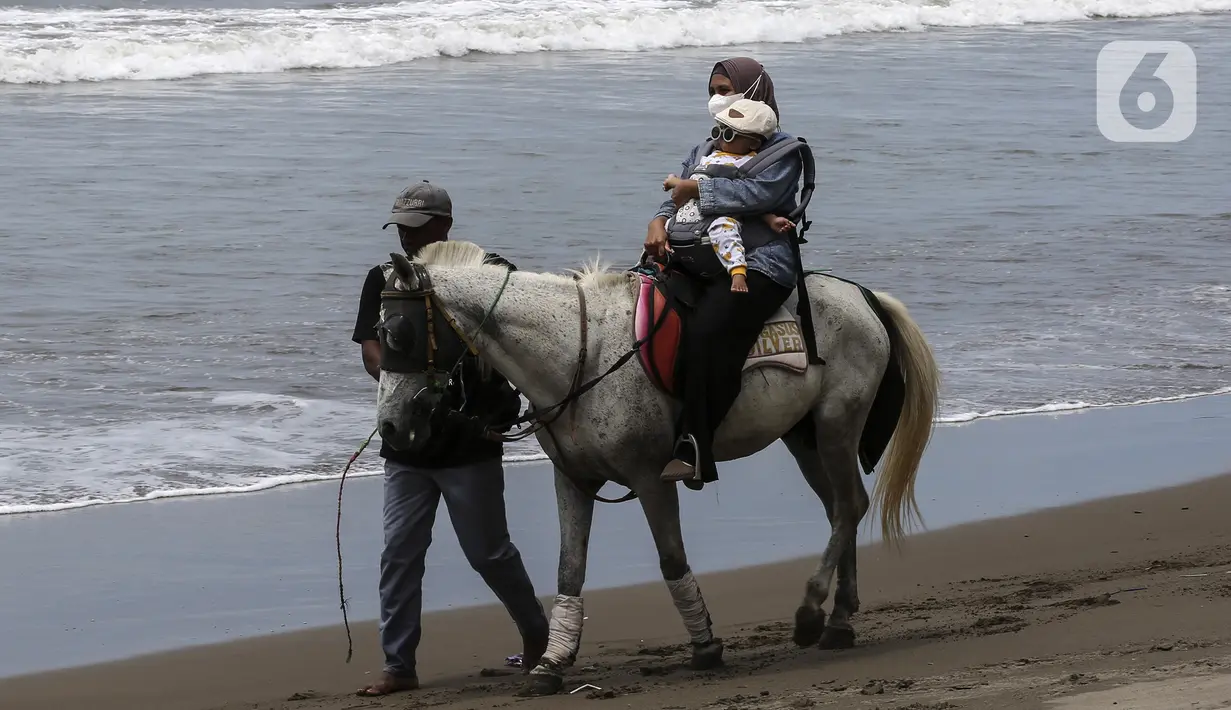 Warga naik kuda di Pantai Pelabuhan Ratu, Kabupaten Sukabumi, Jawa Barat, Jumat (12/11/2021). Penerapan Pemberlakuan Pembatasan Kegiatan Masyarakat (PPKM) Level 1 membolehkan objek wisata kembali buka, salah satunya Pantai Pelabuhan Ratu. (Liputan6.com/Johan Tallo)