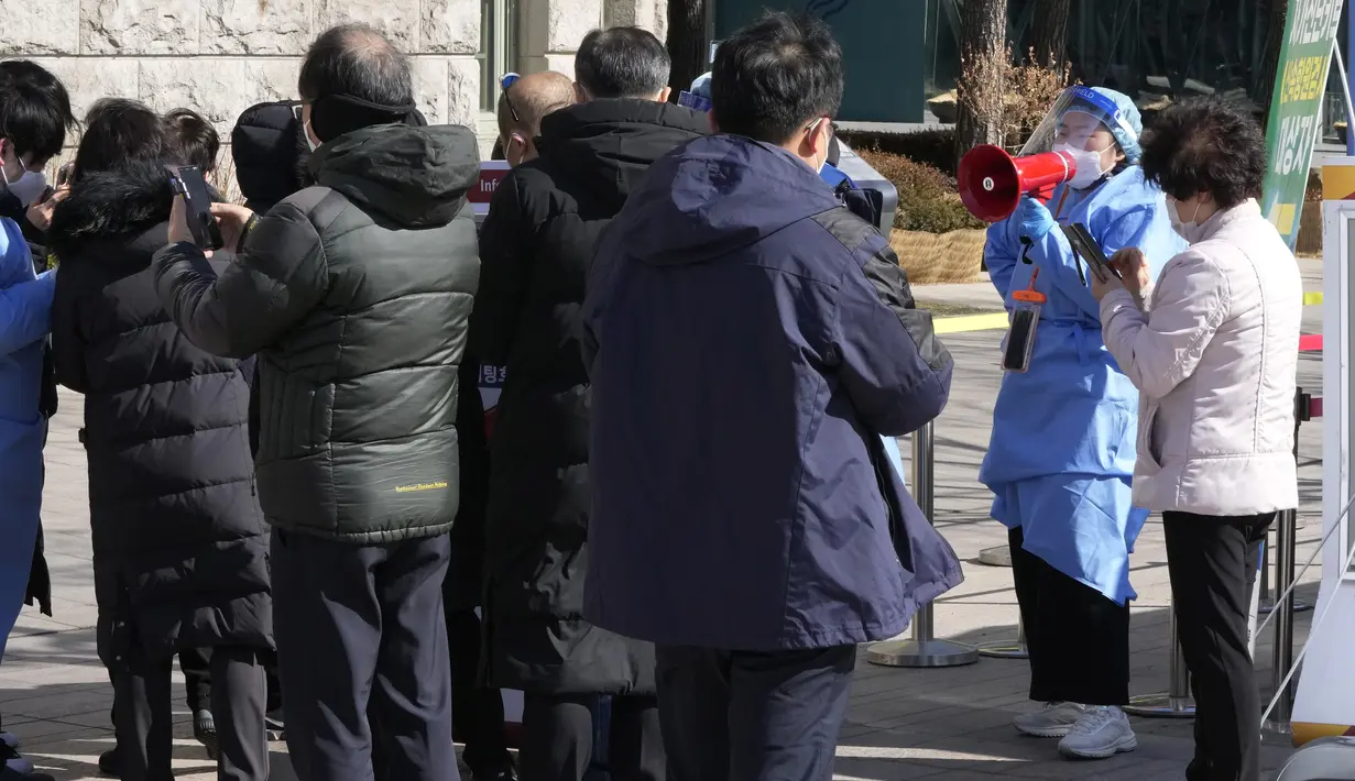 Pekerja medis menggunakan pengeras suara saat orang-orang menunggu tes virus corona di tempat pengujian darurat di Seoul, Rabu (23/2/2022). Kasus harian COVID-19 baru Korea Selatan mencapai rekor tertinggi, melonjak menjadi 171.452 dari 99.569 kasus sehari sebelumnya. (AP Photo/Ahn Young-joon)