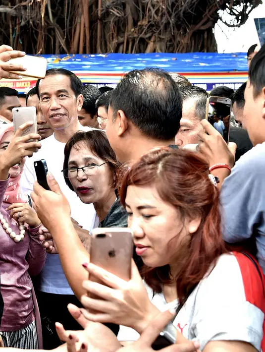 Warga meminta berfoto bersama Presiden Joko Widodo (Jokowi) yang sedang berjalan-jalan di kawasan Malioboro, Yogyakarta, Minggu (31/12). Kunjungan Jokowi ini menarik perhatian warga yang beraktifitas di sekitar kawasan itu. (LIputan6.com/Biro Setpres)
