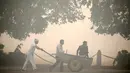 Pekerja mendorong gerobak melitasi taman diselimuti kabut di New Delhi, India (31/10). Sebelumnya, pihak berwenang memperingatkan bahwa Diwali di New Delhi akan terjadi polusi, karena faktor kelembaban dan kecepatan angin. (Reuters/Cathal McNaughton)