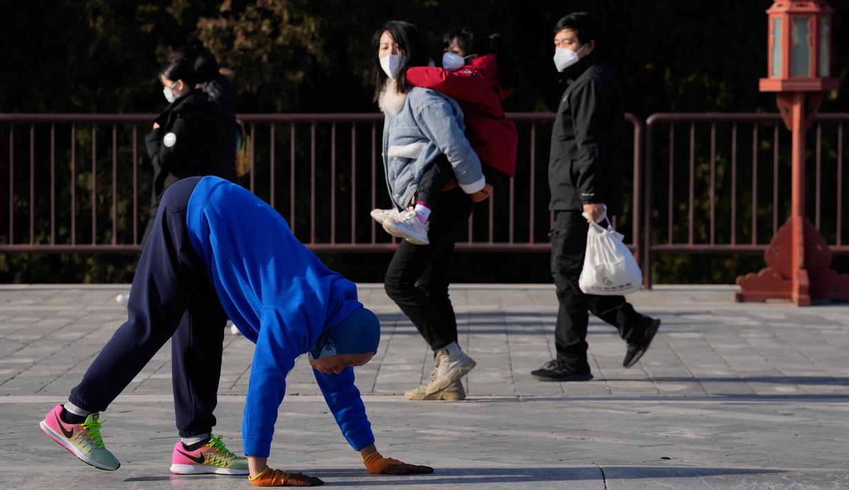 Pengunjung yang memakai masker menyaksikan seorang warga berjalan dengan keempat anggota tubuhnya sebagai bentuk latihan di Temple of Heaven, Beijing, China, Kamis (8/12/2022). China mengumumkan pelonggaran nasional dari pembatasan garis keras COVID-19 pada 7 Desember 2022. (AP Photo/Ng Han Guan)