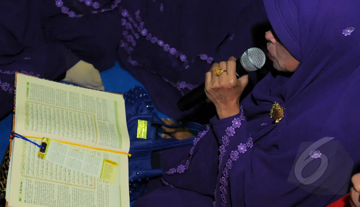 Seorang ibu tampak membaca kitab suci saat menghadiri pengajian yang diselenggarakan oleh KPK, Jakarta, Selasa (17/2/2015).Dalam pengajian ini mereka berharap KPK dan Polri kembali tentram (Liputan6.com/Faisal R Syam)