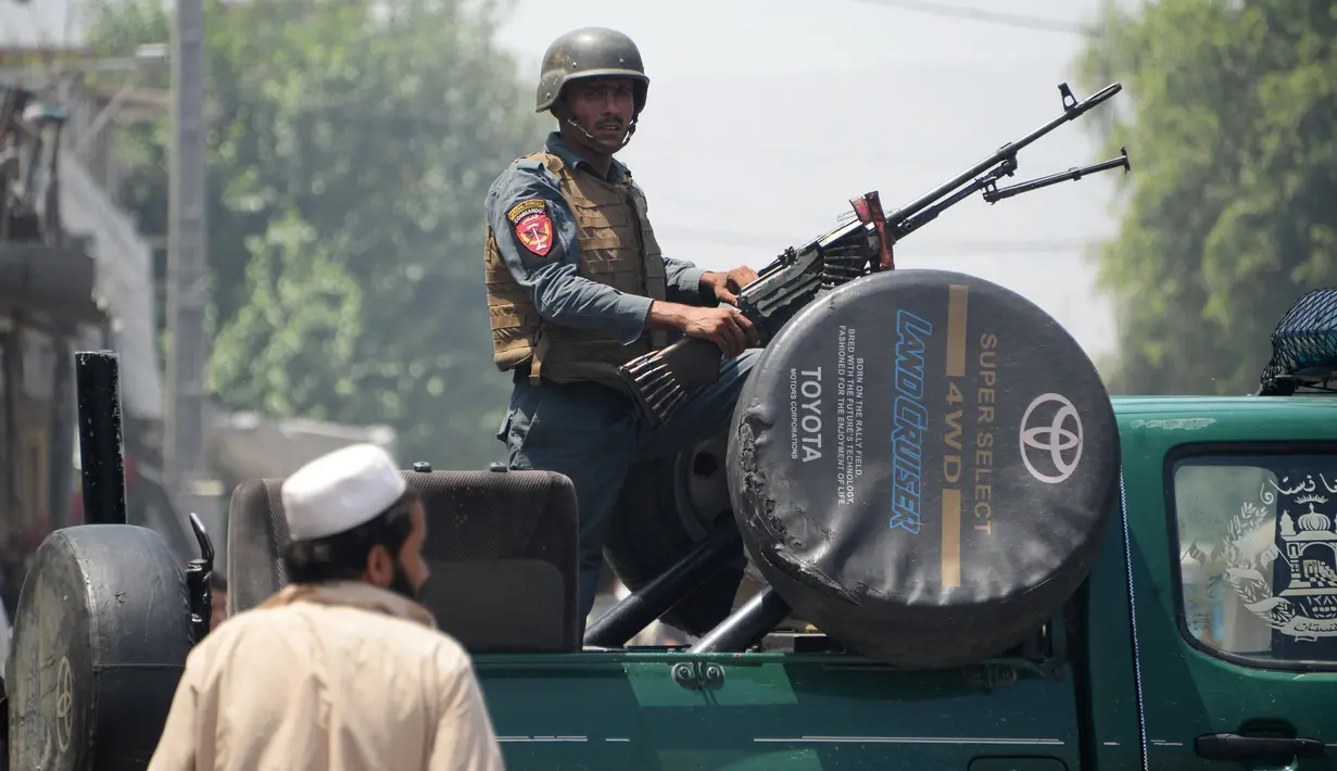 Petugas keamanan Afghanistan berjaga di atas sebuah kendaraan dekat ledakan bom bunuh diri dan serangan bersenjata di Jalalabad, Selasa (31/7). Insiden berakhir dengan tewasnya dua pria bersenjata dan banyak bangunan yang hancur. (AFP/NOORULLAH SHIRZADA)