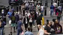 Pejalan kaki dengan masker dan tanpa masker berjalan di sepanjang Las Vegas Strip, di Las Vegas Selasa (27/4/2021). Warga Amerika Serikat (AS) yang telah menerima vaksin COVID-19 tidak lagi diwajibkan mengenakan masker saat berada di luar ruangan jika tidak ada kerumuman. (AP Photo/John Locher)