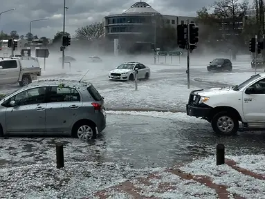 Huja es menutupi kendaraan di persimpangan jalan ibu kota Australia, Canberra pada Senin (20/1/2020). Badai petir dan hujan es menerjang bagian wilayah pantai timur Australia  setelah sebelumnya badai debu melanda daerah-daerah yang dilanda kekeringan. (Tom Swann/The Australia Institute via AP)